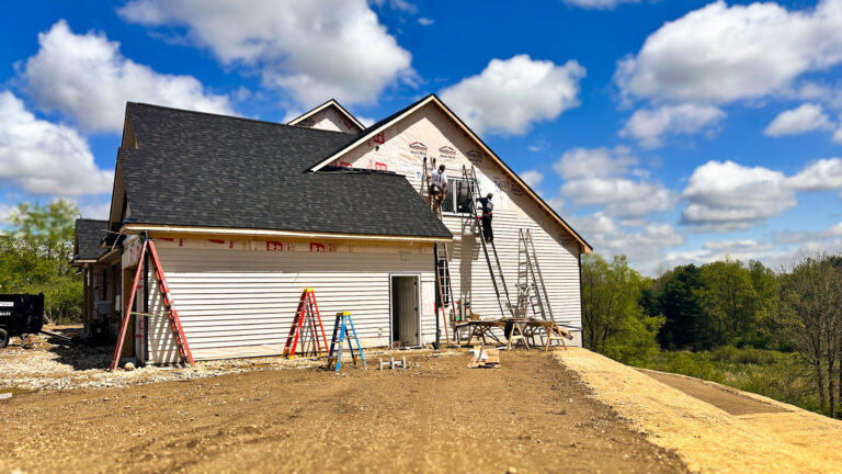 Team installing vinyl siding on new-build home using ladder jacks