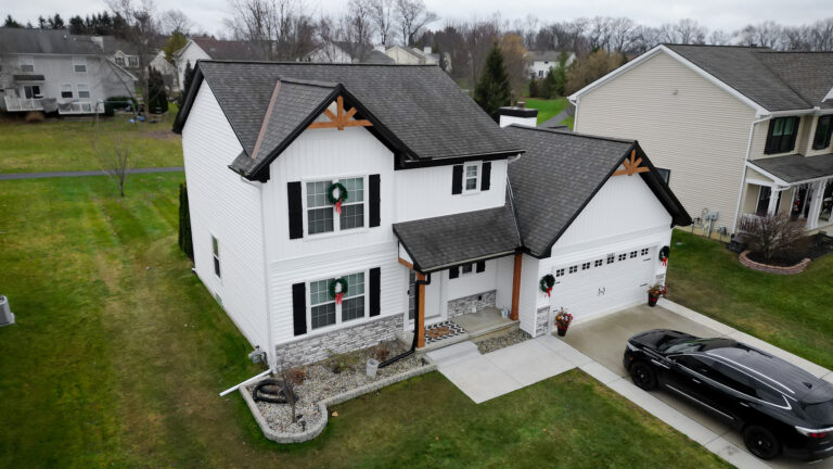 Modern white farmhouse with new charcoal roof, black trim and holiday wreaths