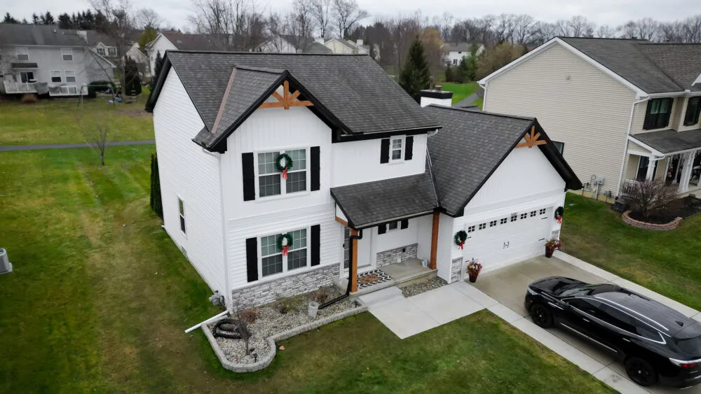 Modern white farmhouse with new charcoal roof, black trim and holiday wreaths